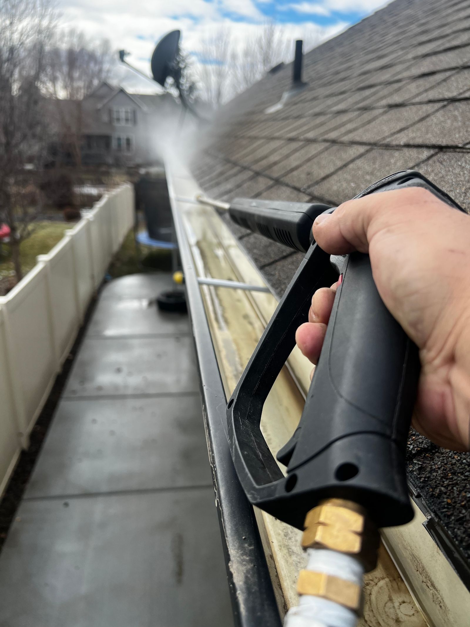 Blocked gutter being cleared on a UK house roofline