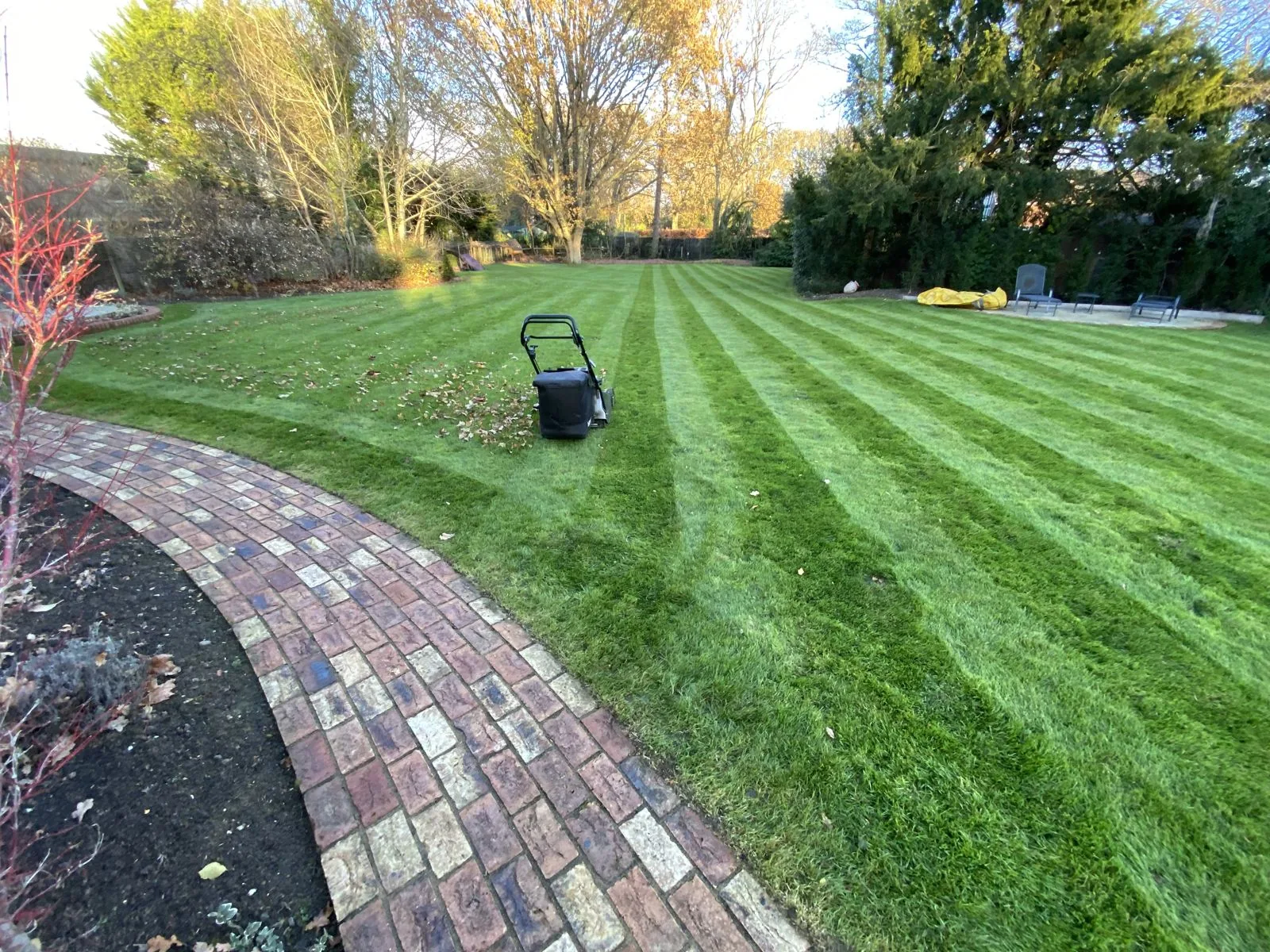 Freshly mown striped lawn beside a curved brick path